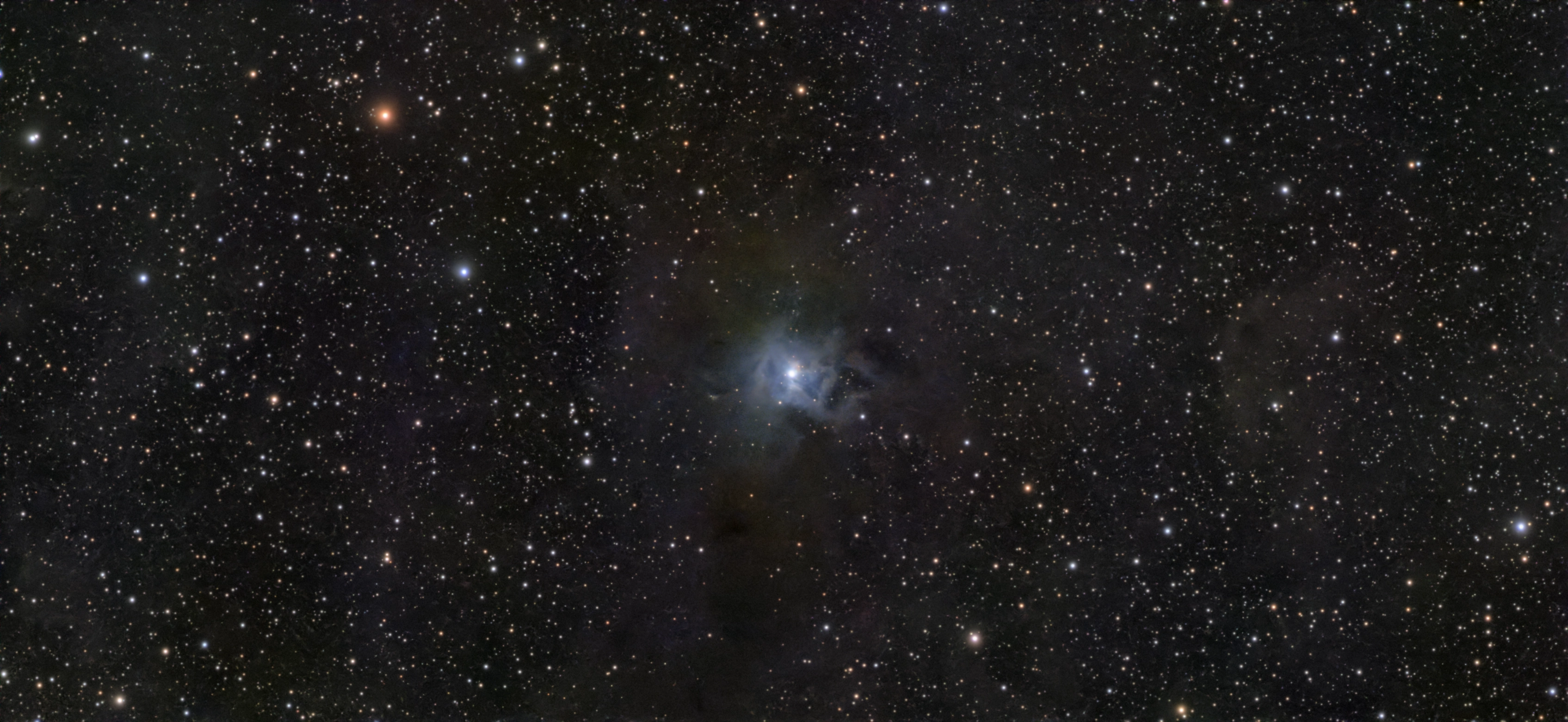 The blue Iris Nebula surrounded by dark dust and stars